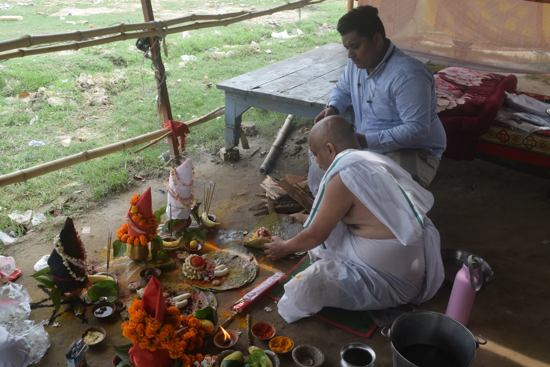 A pandit and participant seated with prepared offerings during Pind Daan