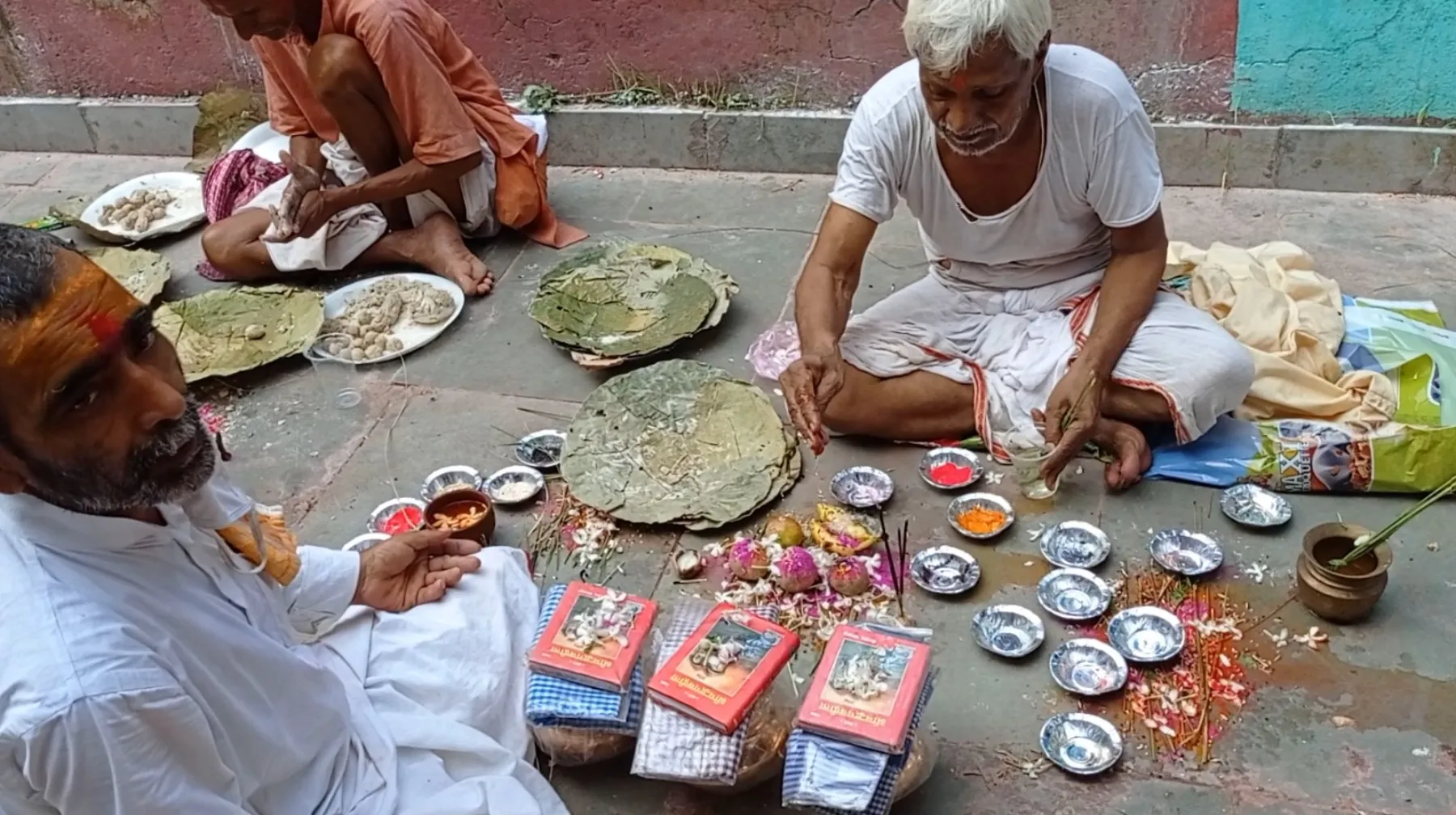 Three participants seated with ritual texts and offerings during Tripindi Shradh