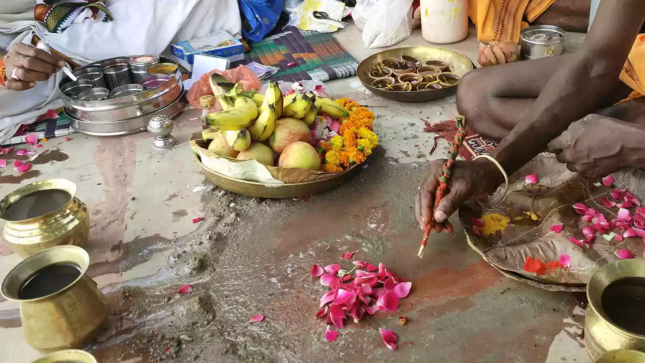 Image of a person doing shradh rituals for their ancestors offer flower petels on floor 