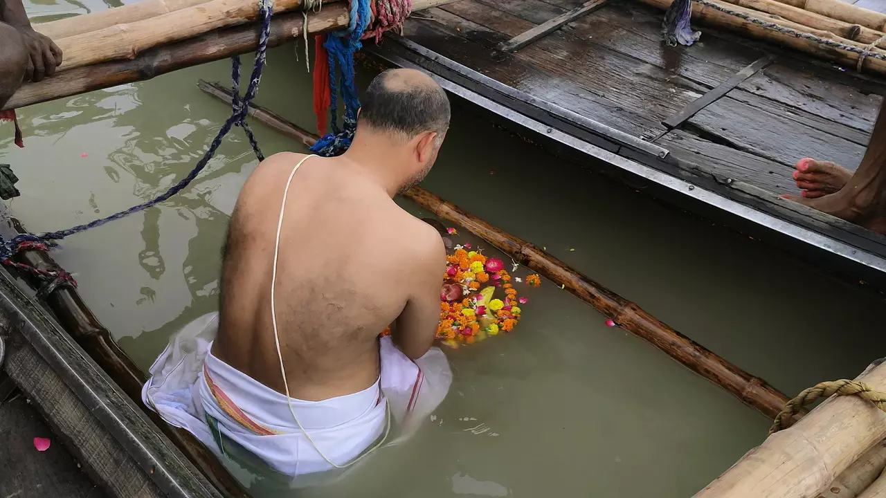 image of a man offering fruits and flowers to ganga river for their ancestors