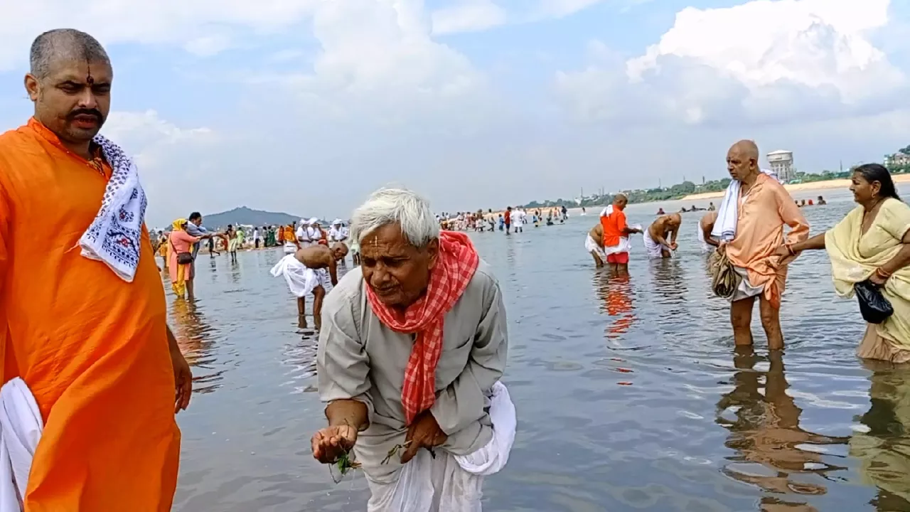 Elderly man performs Tarpan in river, offering water & grass from hands. Another man stands nearby- Tarpan Dos and Donts