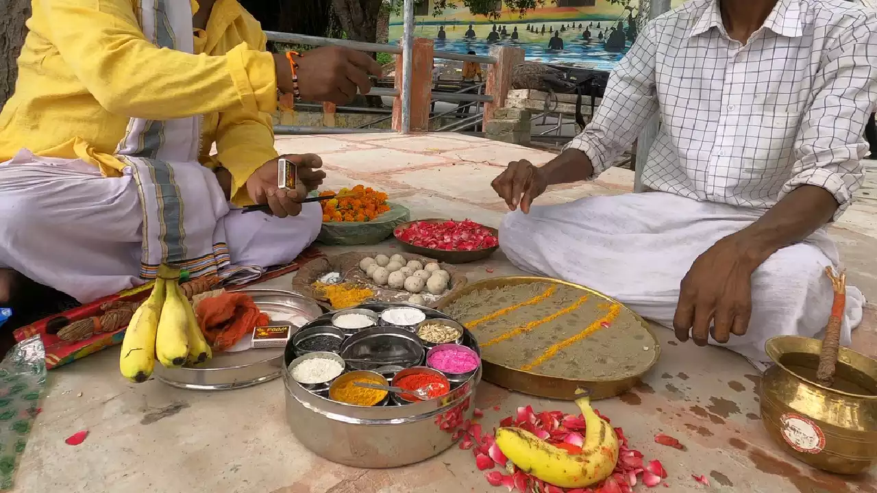 Image of Two men sit for Shradh/Pind Daan with offerings: Pindas, bananas, flowers, powders, sand alta- Pinda symbolism meaning