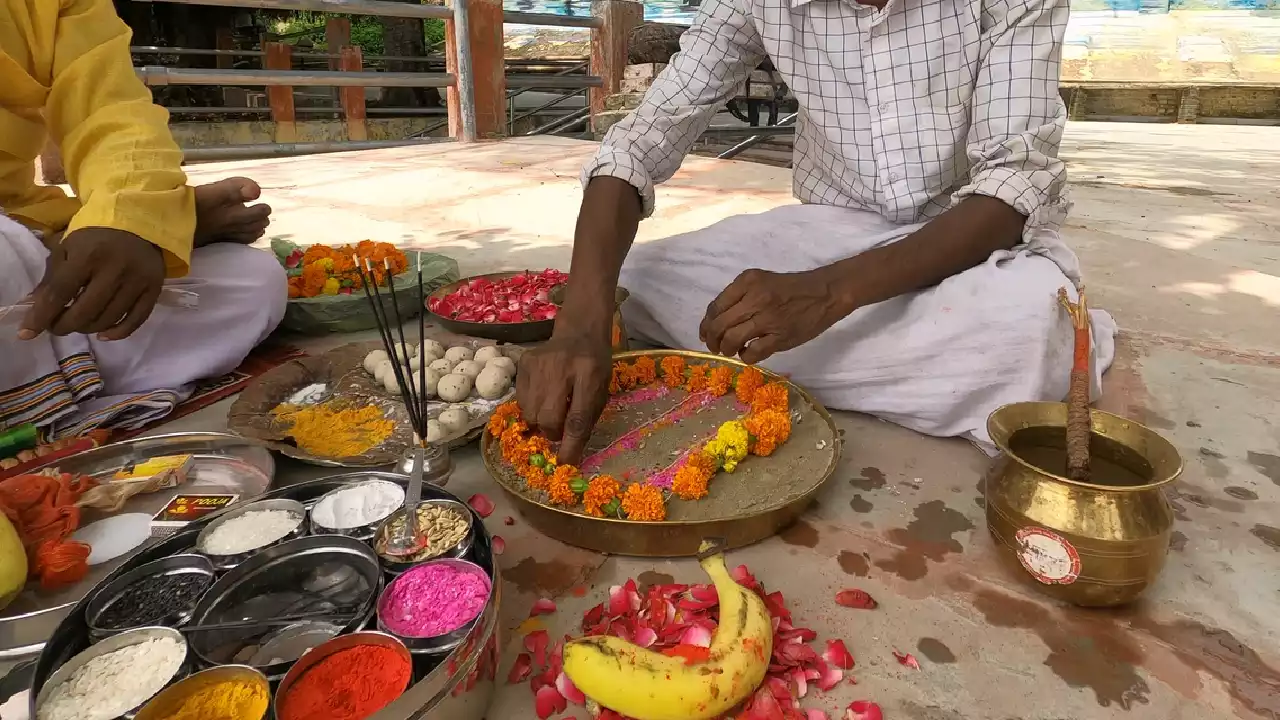 Men performing Pind Daan, decorating sand altar with flowers, powders. Offerings laid out- Purpose of Pind Daan