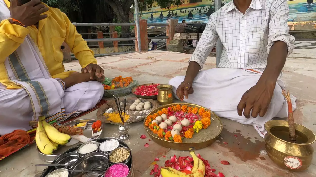 Image of Two men performing Shradh/Pind Daan ritual with offerings: Pindas, flowers, altar, fruit, powders- Who receives Pindas