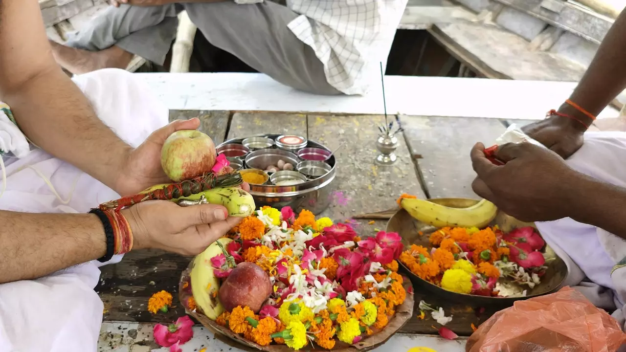 Image of A man hold fruit offerings (apple, parwal) over flowers during Shraddha ritual- What is Tarpan