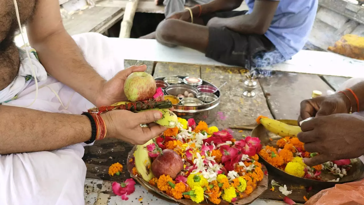 A man hold fruit offerings (apple, parwal) over flowers for sunkalp to do tapan ritual- How to perform Pitru Tarpan ritual