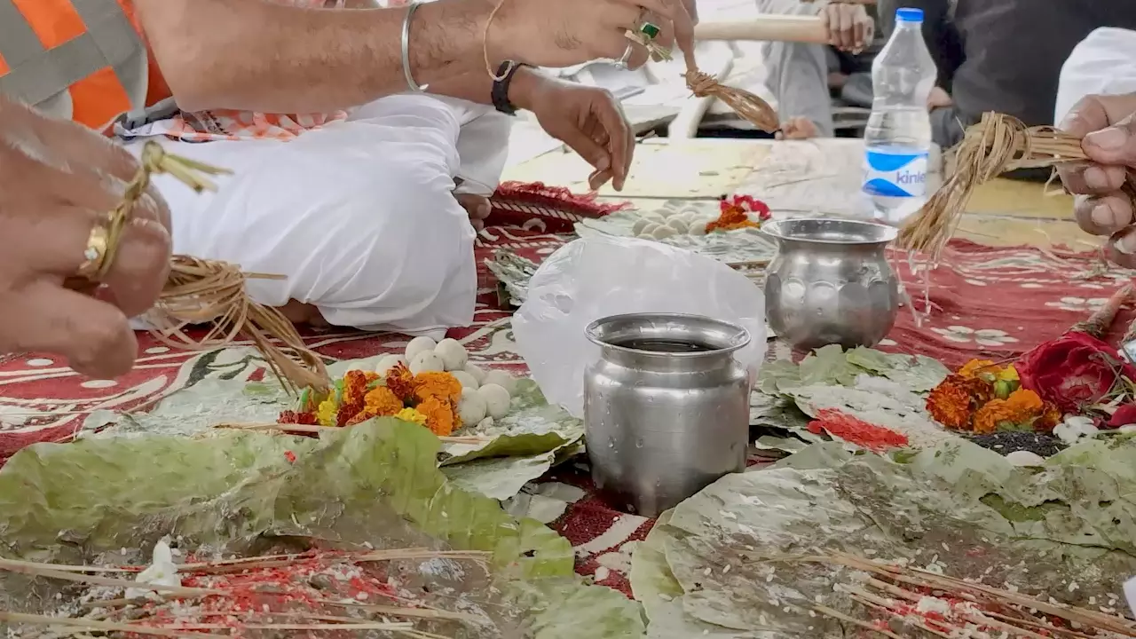 People performing Tarpan with Pindas, Kusha grass, flowers & water pots on leaves. Ritual offerings. 