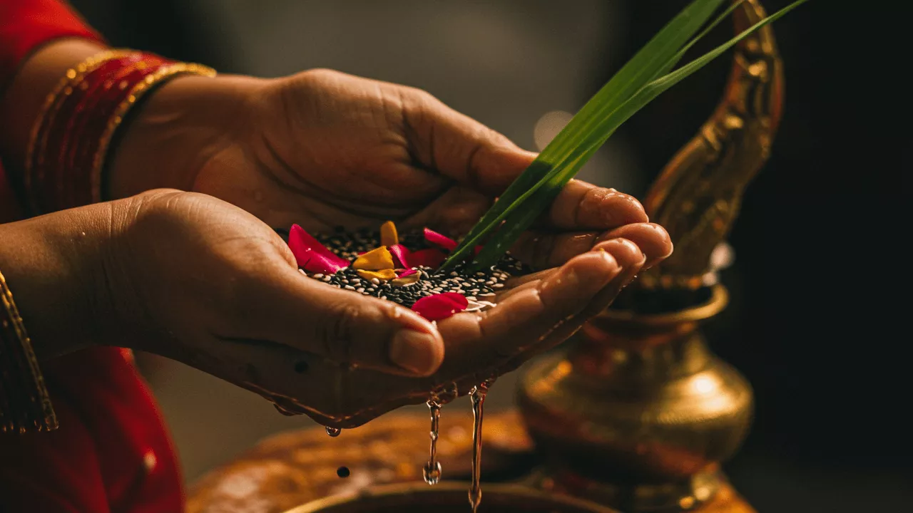 Image of Tarpan ritual: Water drips from hands holding til, flowers & Kusha grass. Brass pot nearby- Tarpan Dos and Donts